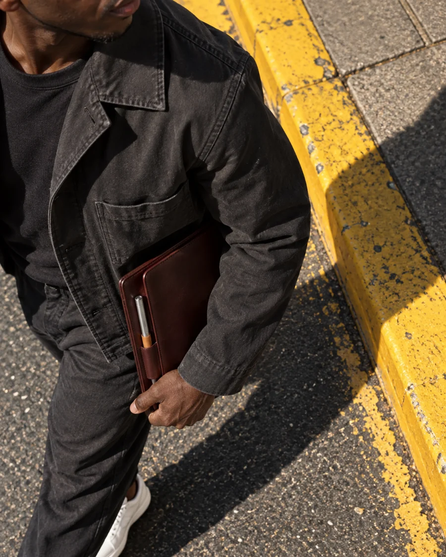 A man walking a city street carrying a portfolio.